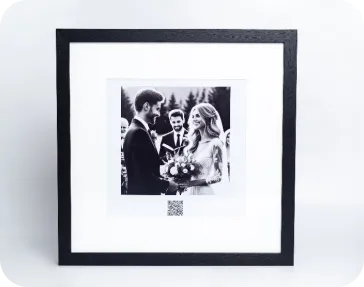 A framed print of a wedding with a QR code below the picture